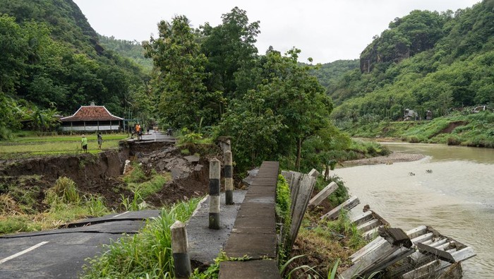 Warga berjalan melewati area persawahan di dekat jalan penghubung desa yang amblas di Sriharjo, Bantul, DI Yogyakarta, Rabu (26/11/2025). Jalan penghubung desa wisata Sriharjo dengan Selopamioro tersebut kembali amblas sepanjang 17 meter dan mengakibatkan ruas tersebut putus. ANTARA FOTO/Hendra Nurdiyansyah/foc.