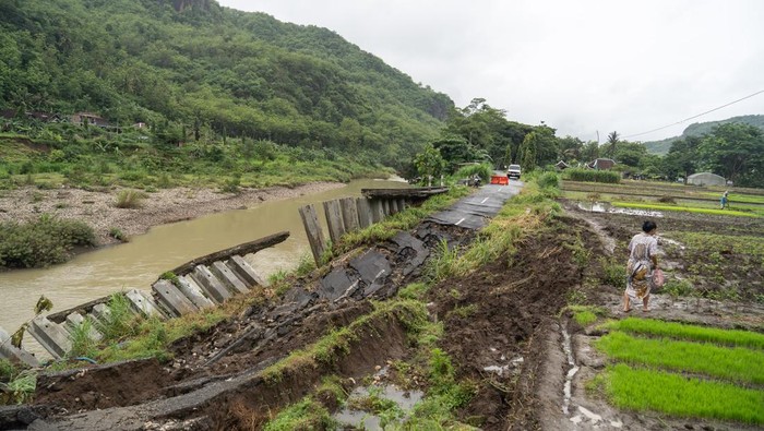 Warga berjalan melewati area persawahan di dekat jalan penghubung desa yang amblas di Sriharjo, Bantul, DI Yogyakarta, Rabu (26/11/2025). Jalan penghubung desa wisata Sriharjo dengan Selopamioro tersebut kembali amblas sepanjang 17 meter dan mengakibatkan ruas tersebut putus. ANTARA FOTO/Hendra Nurdiyansyah/foc.