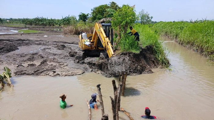 Perbaikan tanggul Kali Lamong yang jebol.