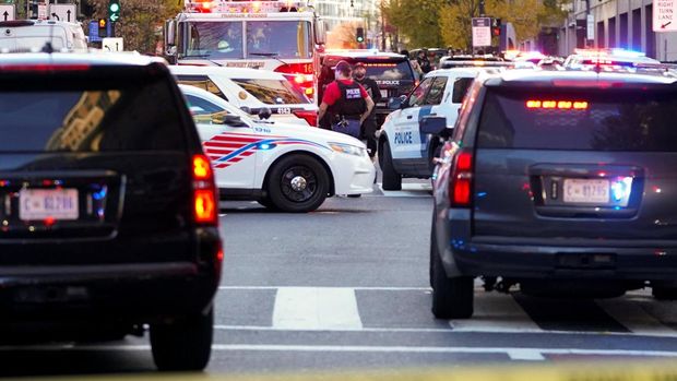 Seorang petugas penegak hukum berjalan di tengah kendaraan polisi, setelah dua anggota Garda Nasional ditembak di dekat Gedung Putih di Washington, D.C., AS, 26 November 2025. (REUTERS/Nathan Howard)