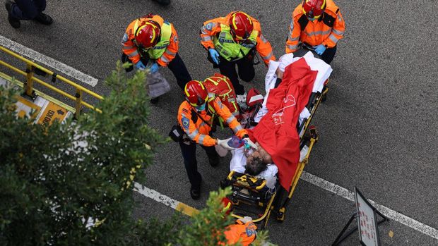 Seorang warga yang terluka dibawa ke ambulans setelah kebakaran besar melanda perancah bambu di beberapa blok di perumahan Wang Fuk Court, menewaskan sedikitnya 44 orang dan menyebabkan hampir 300 orang hilang, di Tai Po, Hong Kong, Tiongkok, 27 November 2025. (REUTERS/Tyrone Siu)