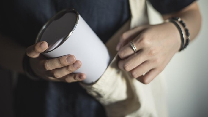 Young woman bringing and taking out tumbler, reusable coffee mug/cup from her bag.