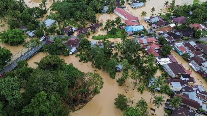Warga melintasi banjir di Kabupaten Solok, Sumatera Barat, Kamis (27/11/2025). Hujan deras yang melanda daerah tersebut selama tiga hari menyebabkan Sungai Batang Lembang dan Sungai Batang Gawan meluap sehingga menyebabkan 598 kepala keluarga atau sebanyak 3.362 jiwa terdampak, serta 224 rumah terendam. ANTARA FOTO/Wawan Kurniawan/Lmo/rwa.