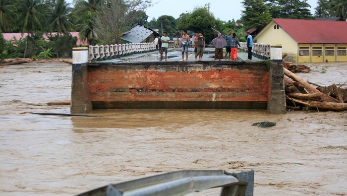 Warga menyaksikan jembatan lintas jalur nasional putus akibat diterjang banjir bandang di Desa Manyang Cut, Kecamatan Mereudu, Kabupaten Pidie, Aceh, Kamis (27/11/2025). Gubernur Aceh Muzakir Manaf menetapkan status darurat bencana hidrometerologi setelah 16 kabupaten/kota di Aceh dilanda banjir hingga longsor, terhitung 28 November hingga 11 Desember 2025. ANTARA FOTO/Ampelsa/foc.