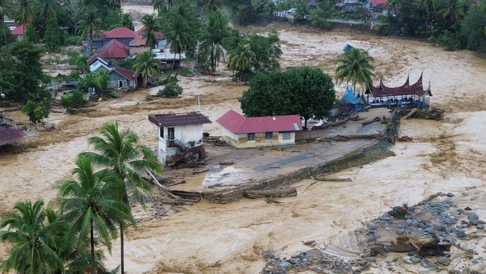 Foto udara sejumlah rumah bendungan diterjang banjir bandang di kawasan Gunung Nago, Padang, Sumatera Barat, Jumat (28/11/2025). Banjir bandang terjadi pada Jumat (28/11/2025) dini hari dan semakin meluas akibat jebolnya bendungan Gunung Nago di Pauh, sehingga mengakibatkan jembatan putus, sejumlah rumah rusak dan warga mengungsi. ANTARA FOTO/Iggoy el Fitra/sgd