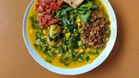 Bubur gurih lain yang populer adalah bubur tinutuan khas Manado. Ini kreasi bubur dengan racikan bumbu rempah kuning yang dimasak bersama bayam, kangkung, daun gedi, jagung, dan ubi. Biasanya disajikan dengan ikan asin, sambal, dan tahu goreng. Foto: iStock/site news