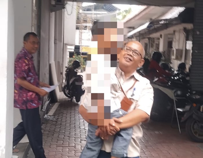 Kasi Rehabilitasi Sosial Dinas Sosial Gresik Alvi Ariyanto menggendong anak yang dijadikan jaminan utang oleh ayah kandungnya.