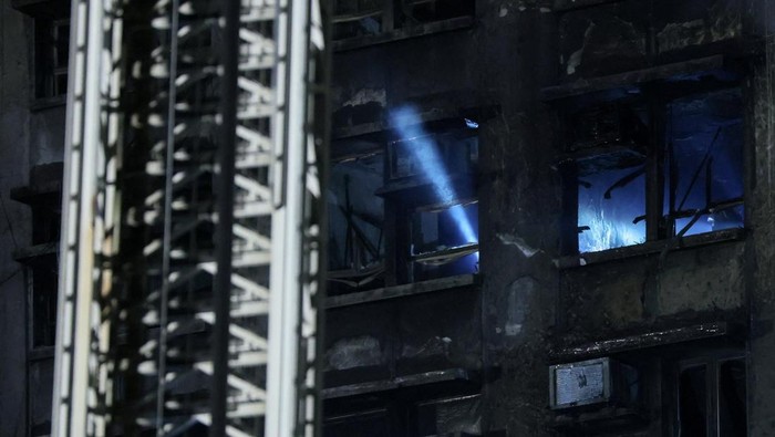 A man walks near the scene of a deadly fire, which broke out yesterday at Wang Fuk Court housing complex, as efforts to extinguish it continue, in Hong Kong, China November 27, 2025. REUTERS/Maxim Shemetov     TPX IMAGES OF THE DAY