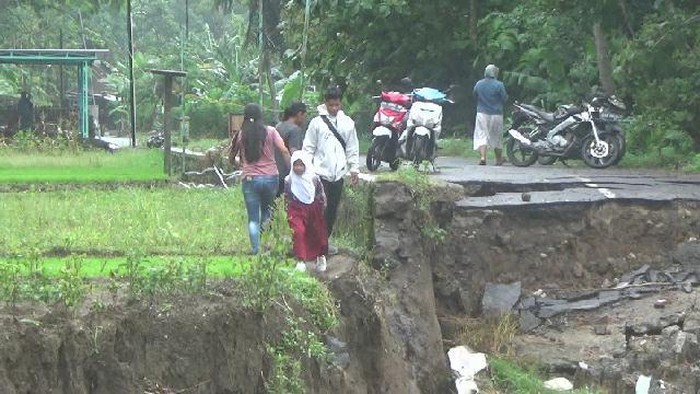 Murid-murid yang harus melewati jalan setapak di sisi utara jalan Kedungmiri yang amblas untuk sekolah. Foto diunggah 28/11/2025).
