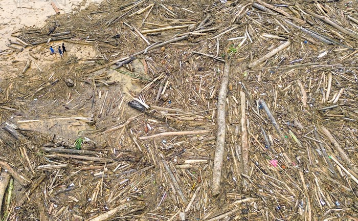 Sejumlah warga berjalan di antara potongan kayu gelondongan yang bertumpuk di pantai Air Tawar, Padang, Sumatera Barat, Jumat (28/11/2025). Sampah kayu gelondongan itu menumpuk di sepanjang pantai Padang pasca banjir bandang beberapa hari terakhir. ANTARA FOTO/Iggoy el Fitra/YU