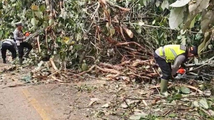 Polisi saat melakukan pembersihan jalan yang tertutup material longsor.