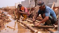 Pantauan di lokasi memperlihatkan mereka menata material bambu serta merapikan tanah merah di sepanjang tanggul sebagai persiapan konstruksi.   