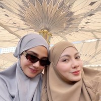Selama umrah Syifa tampil tertutup kenakan hijab. Penampilannya terlihat simpel dengan pilihan busana dan hijab polos. Melengkapi penampilannya, ia mengenakan kaca mata hitam. Foto: Instagram/@syifahadju