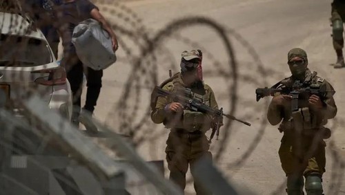 Israeli soldiers stand guard as Syrian Druze people cross back into Syria at the Israeli-Syrian border, in the Israeli-controlled Golan Heights town of Majdal Shams, Thursday, July 17, 2025. (AP Photo)