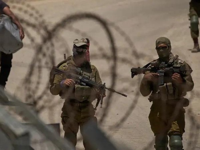 Israeli soldiers stand guard as Syrian Druze people cross back into Syria at the Israeli-Syrian border, in the Israeli-controlled Golan Heights town of Majdal Shams, Thursday, July 17, 2025. (AP Photo)