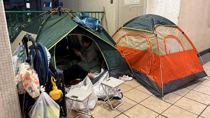 People sit in a tent at a mall, where many residents from a neighbouring apartment had chosen to sleep for the night after being asked to evacuate following a deadly fire at the Wang Fuk Court housing complex, in Hong Kong, China November 27, 2025. REUTERS/David Kirton
