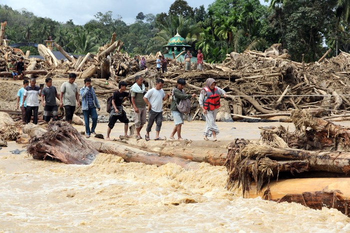 Warga berjalan melintasi sungai dengan jembatan darurat di Desa Aek Garoga, Kecamatan Batang Toru, Kabupaten Tapanuli Selatan, Sumatera Utara, Sabtu (29/11/2025).  Warga terpaksa melintasi jembatan darurat dari batang kayu akibat jalan dan jembatan penghubung antara Kabupaten Tapanuli Selatan menuju Tapanuli Tengah-Sibolga serta Medan putus diterjang banjir bandang pada Selasa (29/11).ANTARA FOTO/Yudi Manar/bar