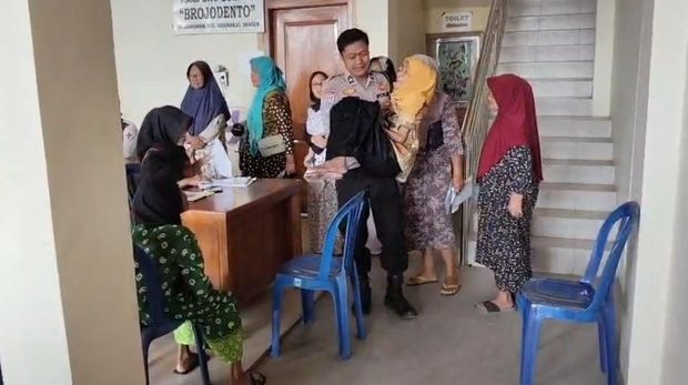 Bhabinkamtibmas di Desa Pandak, Kecamatan Sidoharjo, Sragen, Aipda Siswadi, saat membopong Waginem untuk mengambil BLT.