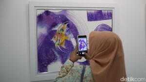 Pengunjung memperhatikan detail sapuan kuas pada salah satu karya, menikmati ragam ekspresi visual yang dihadirkan para pelukis dalam pameran.Bahasa Sanskerta mengartikan Ranjana sebagai rasa yang muncul dari kesadaran berlandas hati, selain perjuangan dan pencarian bahasa visual tak henti. Mohammad Farrel/detikFoto