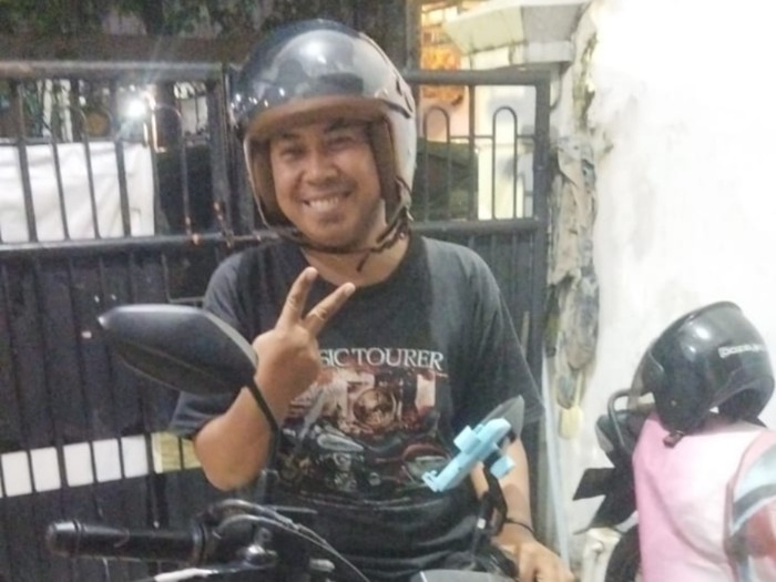 Driver ojol Surabaya Andreas bersama motor lamanya.