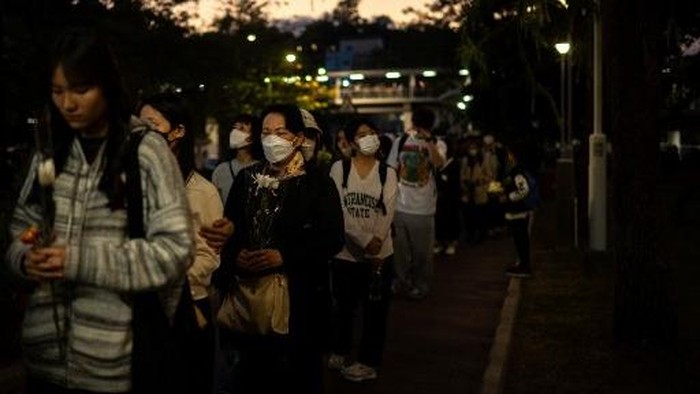People line up to offer flowers outside the Wang Fuk Court in the aftermath of the deadly November 26 fire in Hong Kongs Tai Po district on November 29, 2025. An outpouring of grief was set to sweep Hong Kong on November 29 as an official, three-day mourning period began with a moment of silence for the 128 people killed in one of the citys deadliest fires. (Photo by Philip FONG / AFP)