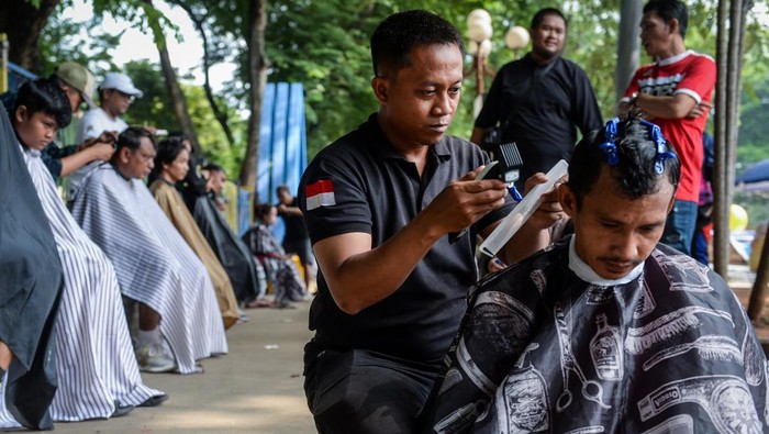 Kapster mencukur rambut warga saat aksi sosial pangkas rambut bayar seikhlasnya di Alun-alun Ahmad Yani, Kota Tangerang, Banten, Minggu (30/11/2025). Aksi yang dilakukan oleh 15 kapster alumni Balai Latihan Kerja Kota Tangerang tersebut untuk mengumpulkan dana bantuan yang hasilnya akan disumbangkan bagi korban bencana alam di Aceh, Sumatera Utara dan Sumatera Barat. ANTARA FOTO/Putra M. Akbar