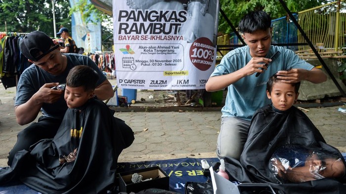 Kapster mencukur rambut warga saat aksi sosial pangkas rambut bayar seikhlasnya di Alun-alun Ahmad Yani, Kota Tangerang, Banten, Minggu (30/11/2025). Aksi yang dilakukan oleh 15 kapster alumni Balai Latihan Kerja Kota Tangerang tersebut untuk mengumpulkan dana bantuan yang hasilnya akan disumbangkan bagi korban bencana alam di Aceh, Sumatera Utara dan Sumatera Barat. ANTARA FOTO/Putra M. Akbar
