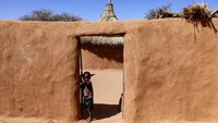 Di antara tenda-tenda dan rumah-rumah sederhana yang terbuat dari lumpur, seorang anak laki-laki berdiri di depan tempat tinggal keluarganya. REUTERS/Amr Abdallah Dalsh