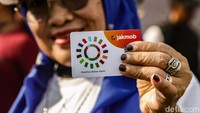 Salah seorang warga menunjukkan kartu JakMob, di kawasan CFD di Jl Imam Bonjol, Jakarta, Minggu (30/11/2025).