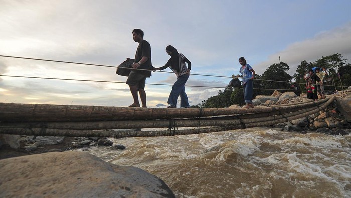 Warga menyeberangi jembatan darurat di atas aliran Sungai Nanggang di Nagari Salareh Aia Timur, Palembayan, Agam, Sumatera Barat, Minggu (30/11/2025). Jembatan darurat dari pohon pinang yang menghubungkan Jorong Pasa menuju Jorong Subarang Aia di Nagari Salareh Aia Timur itu menjadi satu-satunya akses warga untuk mendapatkan bantuan pascaterputusnya akses jembatan akibat banjir bandang yang terjadi pada Kamis (27/11). ANTARA FOTO/Wahdi Septiawan/nz.