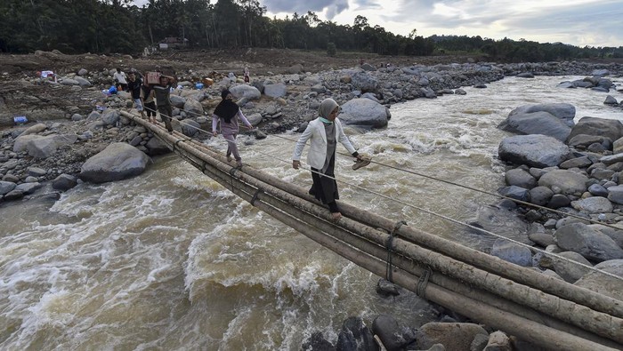 Warga menyeberangi jembatan darurat di atas aliran Sungai Nanggang di Nagari Salareh Aia Timur, Palembayan, Agam, Sumatera Barat, Minggu (30/11/2025). Jembatan darurat dari pohon pinang yang menghubungkan Jorong Pasa menuju Jorong Subarang Aia di Nagari Salareh Aia Timur itu menjadi satu-satunya akses warga untuk mendapatkan bantuan pascaterputusnya akses jembatan akibat banjir bandang yang terjadi pada Kamis (27/11). ANTARA FOTO/Wahdi Septiawan/nz.