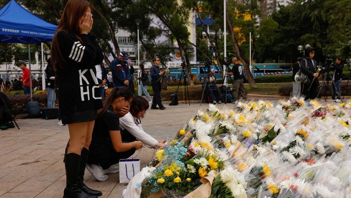 Women cry next to a makeshift flower memorial nearby to the Wang Fuk Court housing complex residents after the deadly fire, in Tai Po, Hong Kong, China, December 1, 2025. REUTERS/Maxim Shemetov