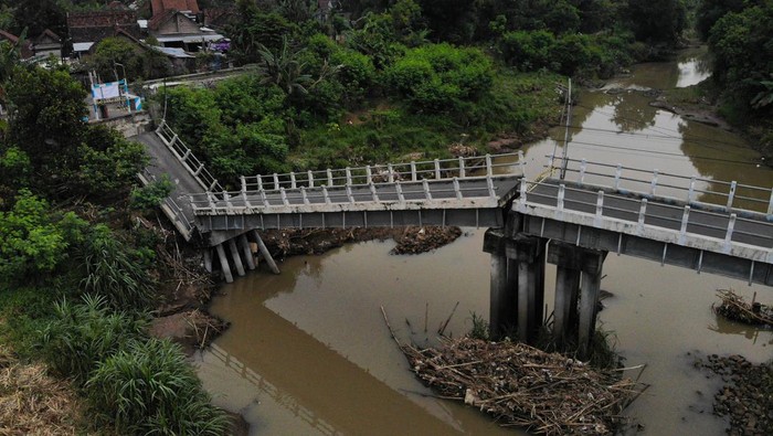 Foto udara kondisi jembatan yang roboh di Kedungdowo, Nganjuk, Jawa Timur, Senin (1/12/2025). Jembatan sepanjang sekitar 60 meter yang dibangun pada tahun 2009 dan menjadi akes utama antar desa itu roboh diduga karena tergerus derasnya aliran sungai. ANTARA FOTO/Muhammad Mada/bar