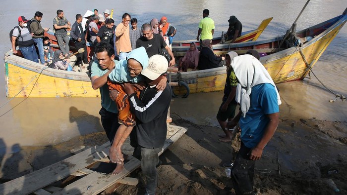 Warga menaiki tangga usai menyeberangi Sungai Tingkeum pascabencana banjir dan meluapnya sungai Tingkeum di Bireuen, Aceh, Senin (1/12/2025). Belasan perahu nelayan membantu warga menyeberangi sungai yang menghubungkan kabupaten Bireuen dan kabupaten Aceh Utara karena terputusnya jembatan Kuta Blang akibat banjir luapan sungai Tingkeum pada 26 November 2025. ANTARA FOTO/Irwansyah Putra