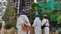 Petugas memantau area sekitar kompleks apartemen bertingkat yang hangus terbakar. Penyelidikan masih berlangsung di tengah sorotan publik terhadap peringatan risiko kebakaran yang diabaikan. Foto: Hong Kong Police Force/Handout via REUTERS
