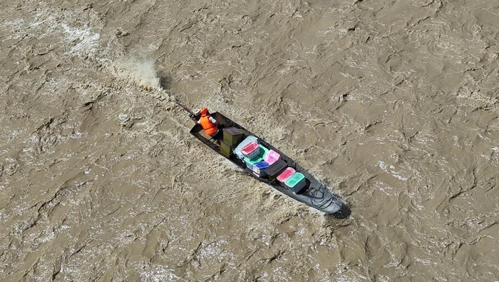Foto udara Sejumlah petugas BPBD Nagan Raya membawa logistik korban banjir bandang untuk didistribusikan ke seberang sungai dengan menggunakan perahu di Desa Blang Meurandeh, Beutong Ateuh Banggalang, Nagan Raya, Aceh, Minggu (30/11/2025). Pemerintah Kabupaten Nagan Raya, TNI/Polri dan stakeholder terus berupaya menyalurkan dan menyuplai logistik untuk korban banjir yang terisolasi berupa air mineral, mie instan, beras, minyak goreng, kebutuhan bayi, tikar dan selimut kepada 2.109 jiwa terdampak. ANTARA FOTO/Syifa Yulinnas/nz.