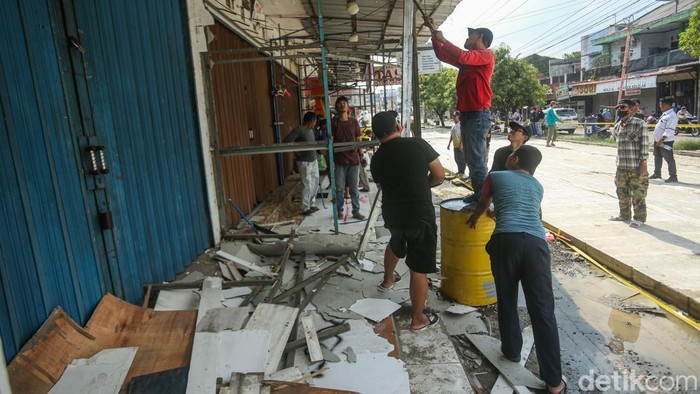 Sejumlah warga bergotong royong menertibkan bangunan yang memakan jalan di Puri Cendana, Tambun Selatan, Bekasi, Minggu (30/11/2025).