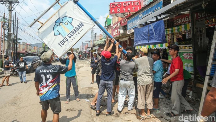 Sejumlah warga bergotong royong menertibkan bangunan yang memakan jalan di Puri Cendana, Tambun Selatan, Bekasi, Minggu (30/11/2025).