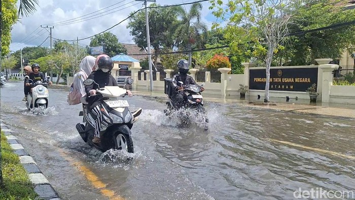 Sejumlah pengendara menerobos genangan air akibat curah hujan tinggi di Jalan Lingkar Selatan, Sekarbela, Kota Mataram, Senin (1/12/2025). (Foto: Nathea Citra/detikBali)