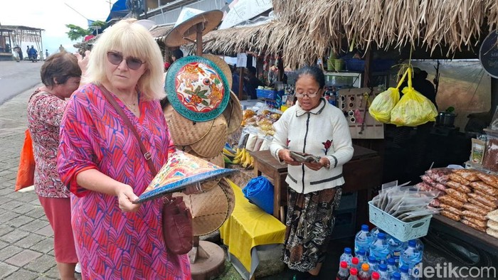 Mbah Anik atau Ni Wayan Suarni saat melayani tamu asing di depan lapaknya di DTW Jatiluwih, Kecamatan Penebel, Tabanan, dengan masih menggunakan kamus.