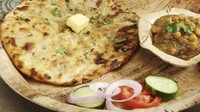 Roti pipih dari India bernama Amritsari Kulca dibuat dengan isian kentang, bawang bombai, keju cottage, dan rempah-rempah. Hidangan ini begitu populer bahkan dijual hampir di seluruh toko. Foto: Taste Atlas