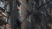 Seorang warga mengeluarkan pecahan kaca dari apartemen milikinya yang terkena serangan drone milik Rusia, berusaha membersihkan yang tersisa. Sampai Selasa kemarin 35 ton puing konstruksi telah dibersihkan, langkah ini memungkinkan akses ke area dalam gedung. REUTERS/Anatolii Stepanov