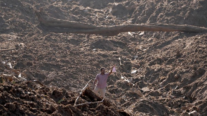 A man holds up a food packet as he moves through mud after landslides triggered by heavy rainfall following Cyclone Ditwah, in Mawathura in Kandy district, Sri Lanka, December 3, 2025. REUTERS/Thilina Kaluthotage