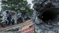 Pesepeda motor melintas di atas proyek galian saluran air depan Cinere Mall, Depok, Jawa Barat, Rabu (3/12/2025).