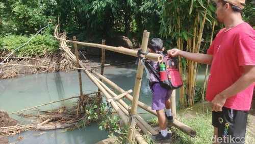 Warga Kelurahan Pendem, Kabupaten Jembrana, Bali, melintasi jembatan darurat yang sudah reyot, Rabu (3/12/2025). (Foto: I Putu Adi Budiastrawan/detikBali)