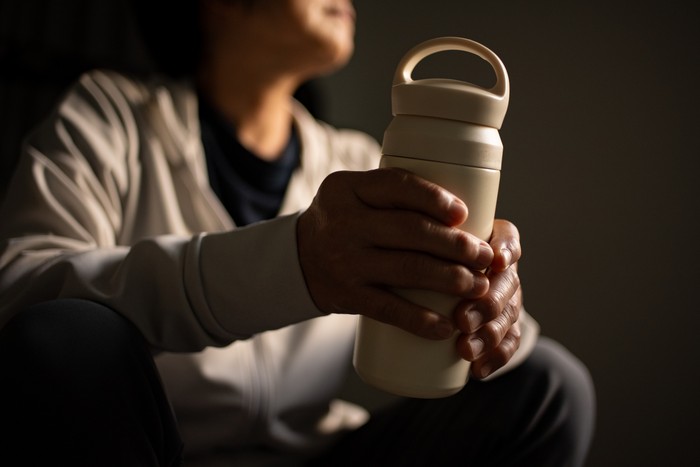 Mature asian woman drinking water while resting after workout.