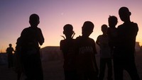Anak-anak pengungsi Sudan berdiri saat hari meredup di Kamp Tine. Senja menyelimuti kamp yang menampung ribuan keluarga yang melarikan diri dari kekerasan di Al-Fashir, sementara kondisi kemanusiaan semakin genting akibat keterbatasan pasokan dan pertempuran yang belum mereda di Sudan. REUTERS/Amr Abdallah Dalsh