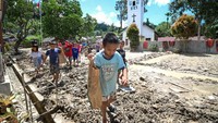 Anak-anak sekolah di Tapanuli Utara berjalan di antara puing sambil menenteng bantuan dari Kemendikdasmen. Foto: (Dokumentasi Kemendikdasmen)