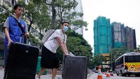 Warga berjalan menjauh dari Wang Chi House sambil membawa harta benda yang berhasil diselamatkan, meninggalkan latar kawasan yang masih dalam pemulihan. Berdasar data sensus, kompleks tersebut menampung lebih dari 4.000 orang. Foto: REUTERS/Maxim Shemetov