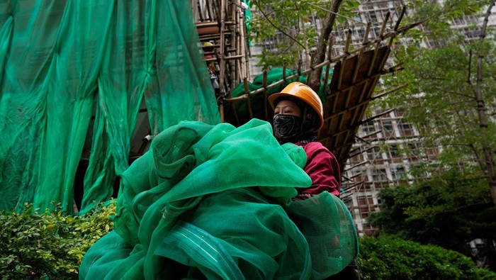 Workers remove scaffolding mesh from a building at Sui Wo Court in Sha Tin, following authorities' decision to remove the netting amid investigations into a deadly fire at Wang Fuk Court, in Hong Kong, China December 4, 2025. REUTERS/Vernon Yuen     TPX IMAGES OF THE DAY